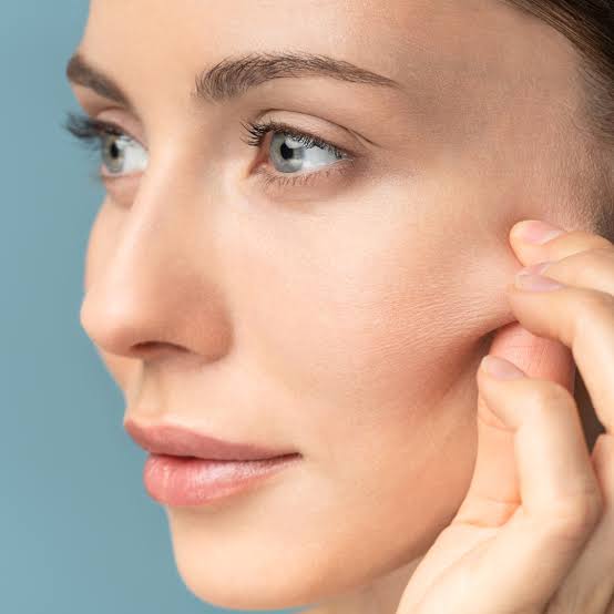 Close-up of a woman touching the skin beside her cheek