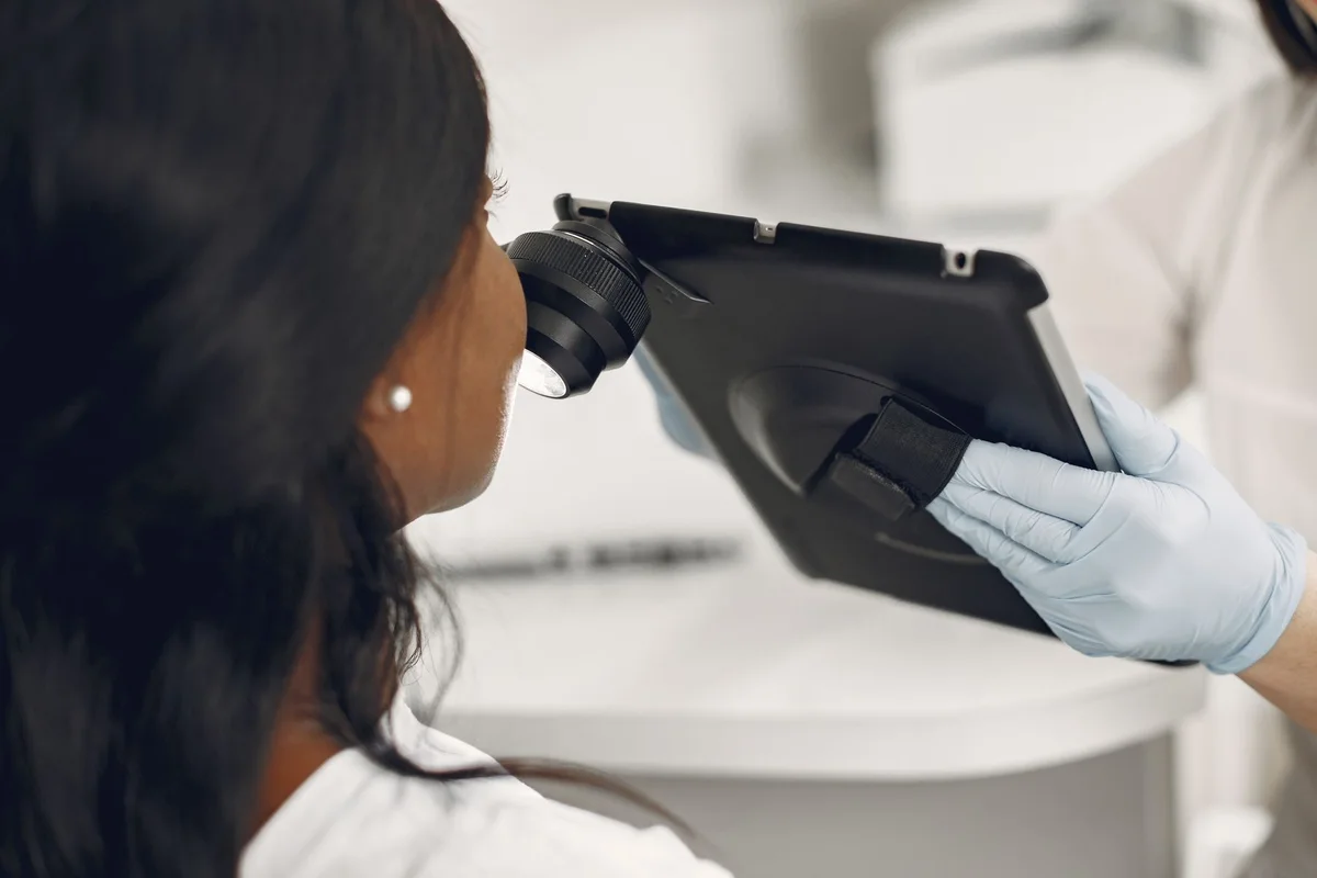 A clinician examines facial skin with a magnifying tablet attachment during a skin assessment